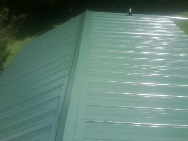 New green metal panels meeting at the ridge of a roof in Butler