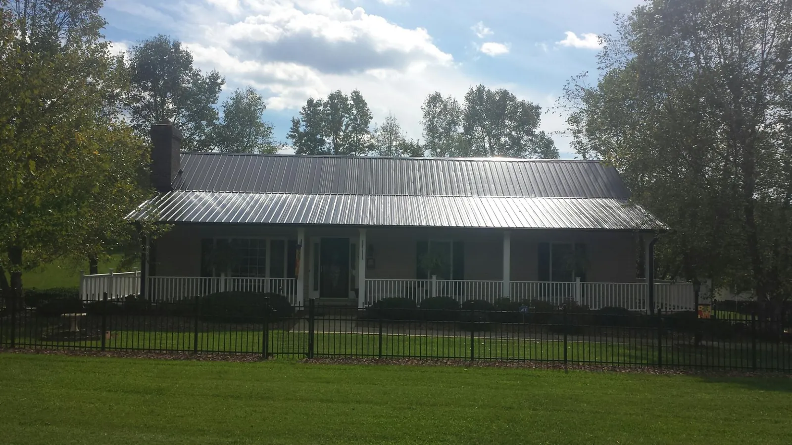 Gray metal roof on a brick ranch with a full width front porch — Gutter Guard Installation work by our crew in Butler